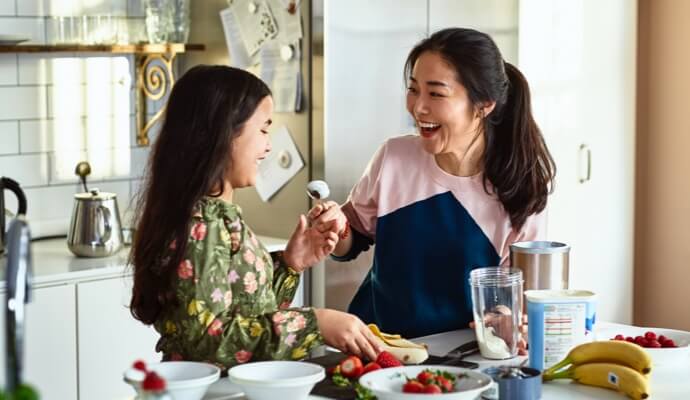 Mulher e criança a rir enquanto preparam comida